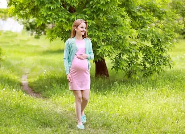 happy pregnant woman walking in a park