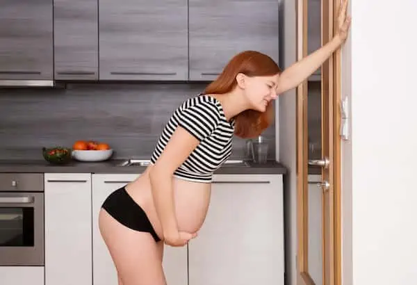 pregnant woman tries to stand with backpain